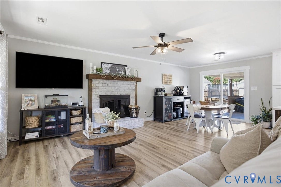 7900 Valencia Road, Chesterfield, VA 23832 Wood-finish flooring, white brick fireplace with a wood mantel, ceiling fan with light fixture, sliding glass door, and recessed lighting