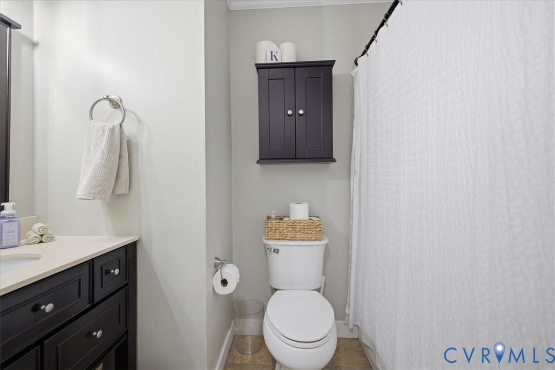 7900 Valencia Road, Chesterfield, VA 23832 Bathroom featuring a dark wood-finish vanity with a light countertop, chrome-finish hardware, a built-in wall cabinet, and an enclosed shower area