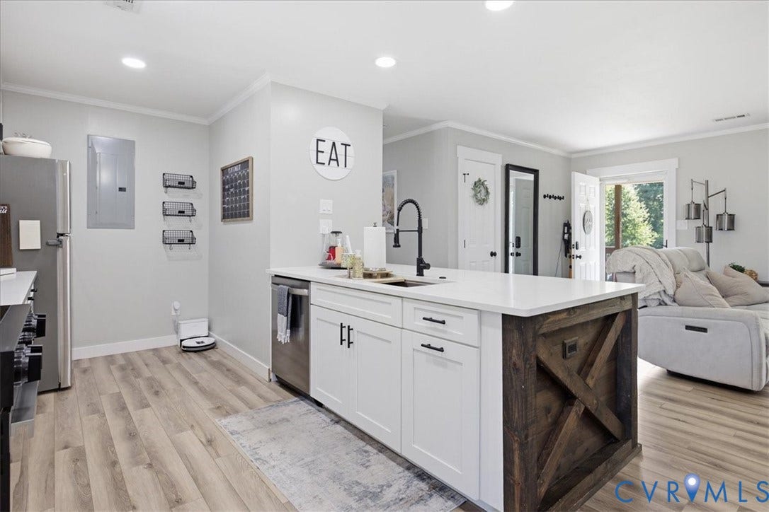 7900 Valencia Road, Chesterfield, VA 23832 Kitchen island featuring a white countertop, farmhouse-style sink with a matte black faucet, white cabinetry, and a dark wood X-frame accent