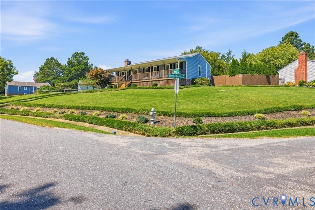 7900 Valencia Road, Chesterfield, VA 23832 Blue siding exterior with an expansive front lawn, elevated wooden porch with railings, and established perimeter landscaping
