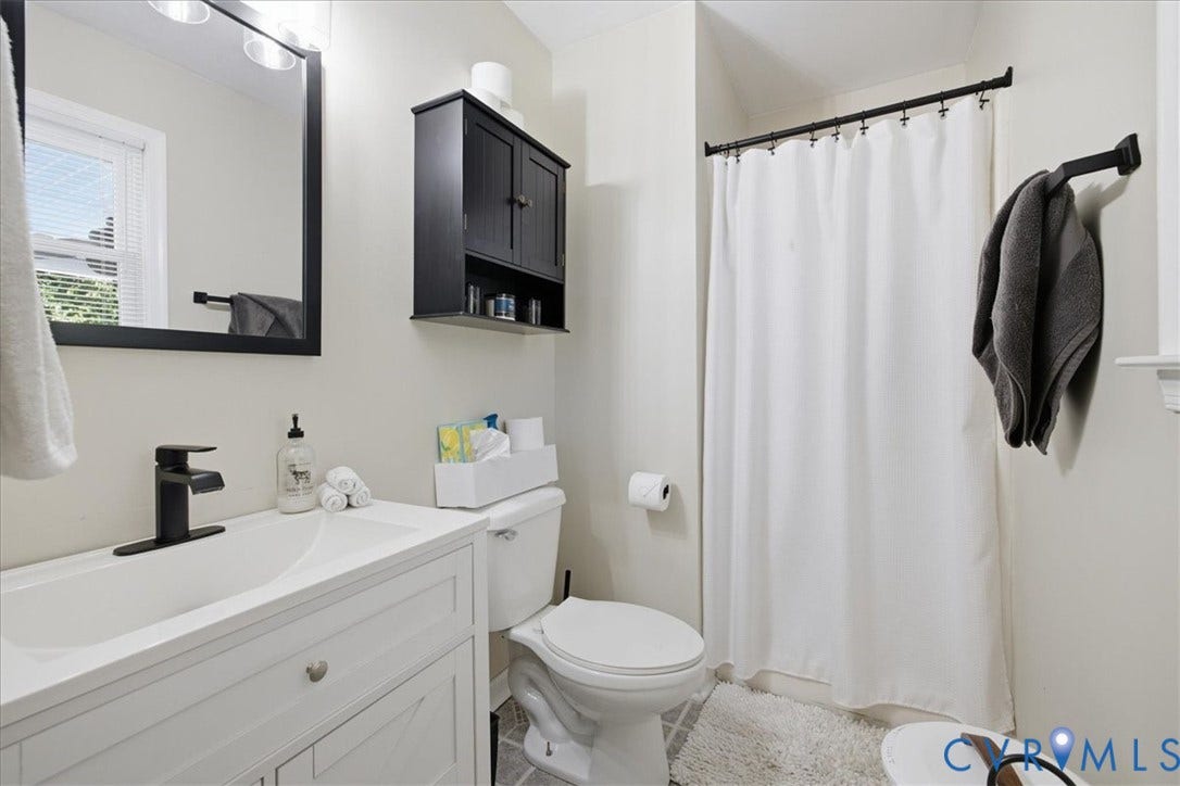 7900 Valencia Road, Chesterfield, VA 23832 Bathroom featuring a white vanity with a single basin sink, matte black faucet, and a wall-mounted mirror