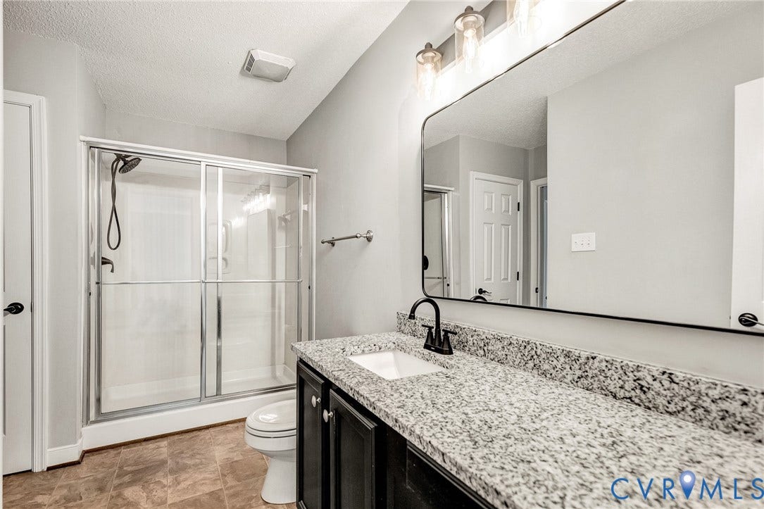 Glass-enclosed shower with dark fixtures