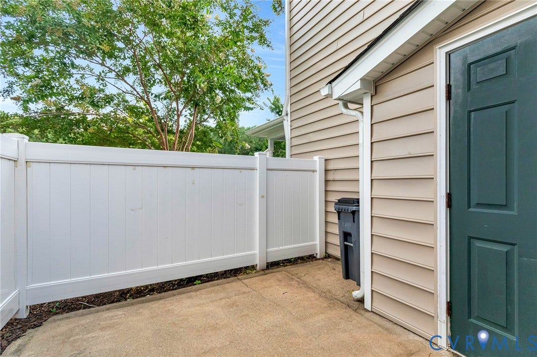 Entryway featuring a white privacy fence, an arched transom window, a clear glass storm door, and a concrete walkway