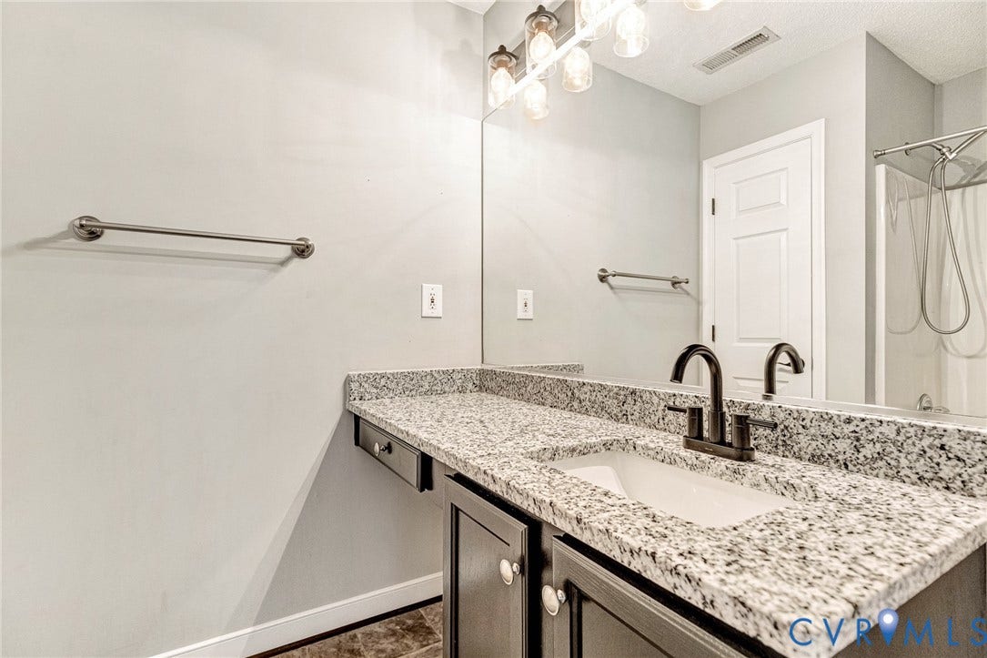 Double vanity featuring granite-finish countertops, an undermount sink, and a dark bronze faucet