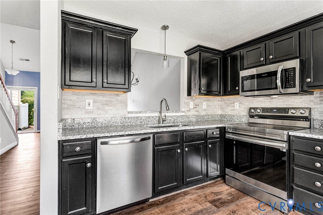 Kitchen featuring dark cabinetry, stainless steel appliances, speckled countertops, and a tiled backsplash