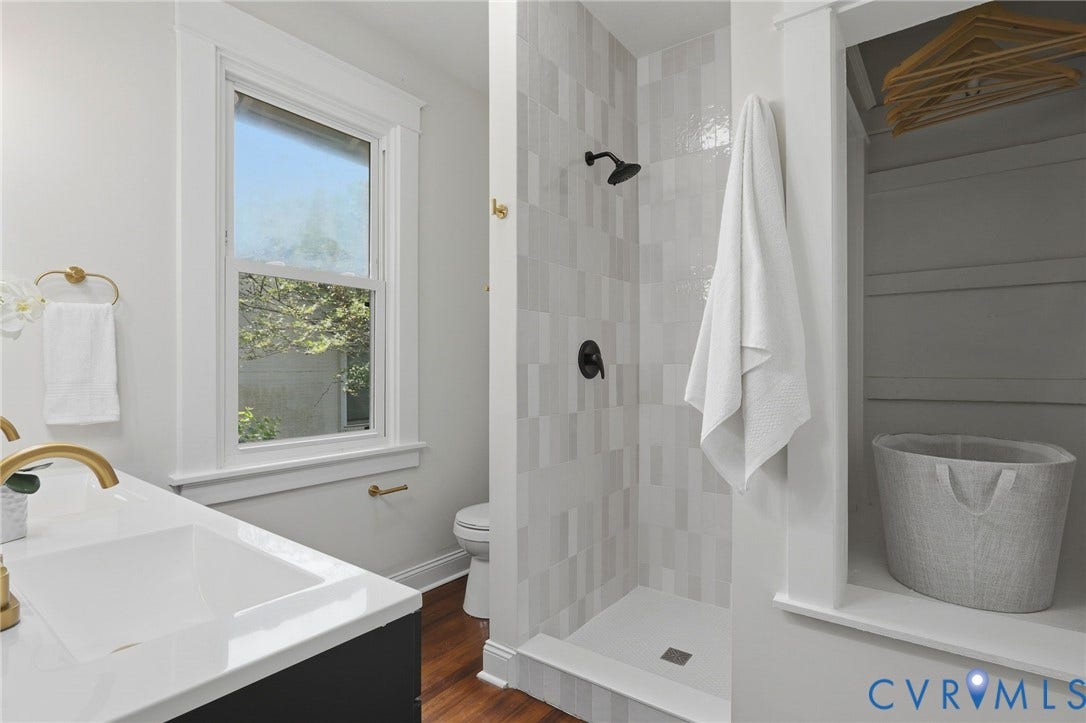 1815 Carlisle Avenue, Richmond, VA 23231 Walk-in shower with vertical tile surround and dark bronze fixtures, single vanity with integrated rectangular sink and gold-finish faucet, and a window providing natural light