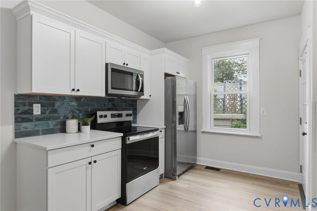 1815 Carlisle Avenue, Richmond, VA 23231 White shaker cabinetry with crown molding, subway tile backsplash, stainless steel appliances, light-toned wood-finish flooring, and a single window