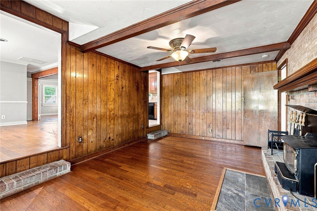 2707 Academy Road, Powhatan, VA 23139 Hardwood flooring, wood paneling, brick fireplace surround, wood-finish ceiling fan, and exposed ceiling beams