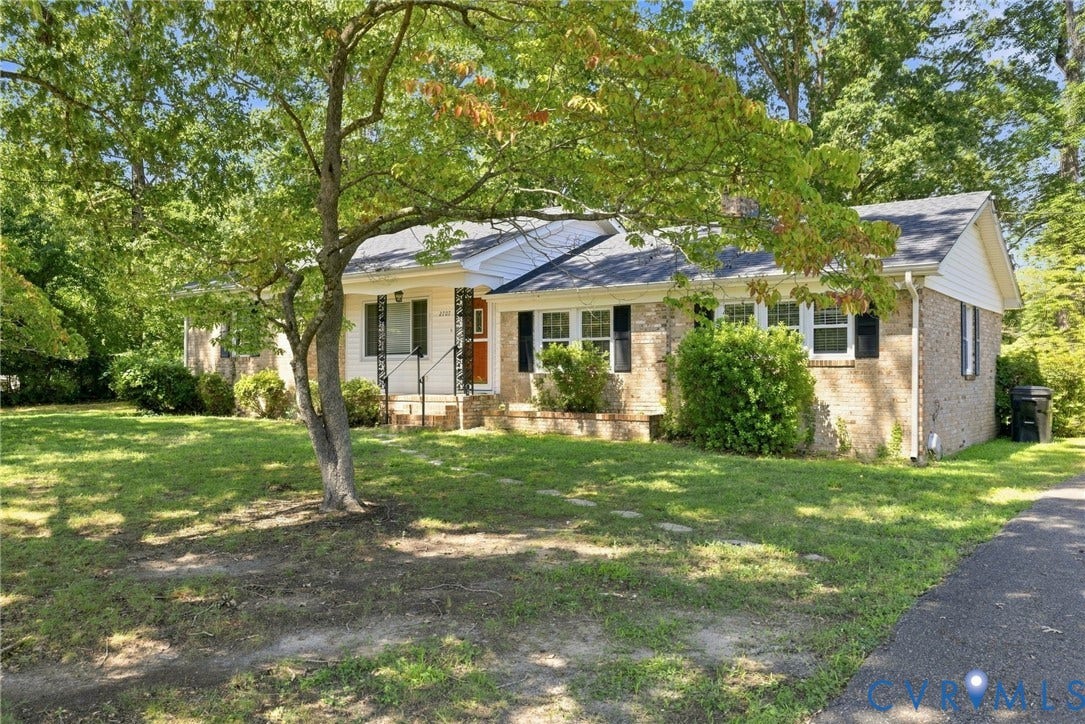 2707 Academy Road, Powhatan, VA 23139 Brick exterior with white siding accents, front porch with wrought iron railing, manicured front lawn, and mature trees