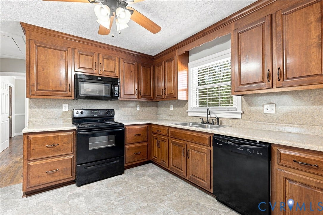 2707 Academy Road, Powhatan, VA 23139 Kitchen featuring wood cabinetry, solid surface countertops, black appliances, a double basin sink, and a ceiling fan