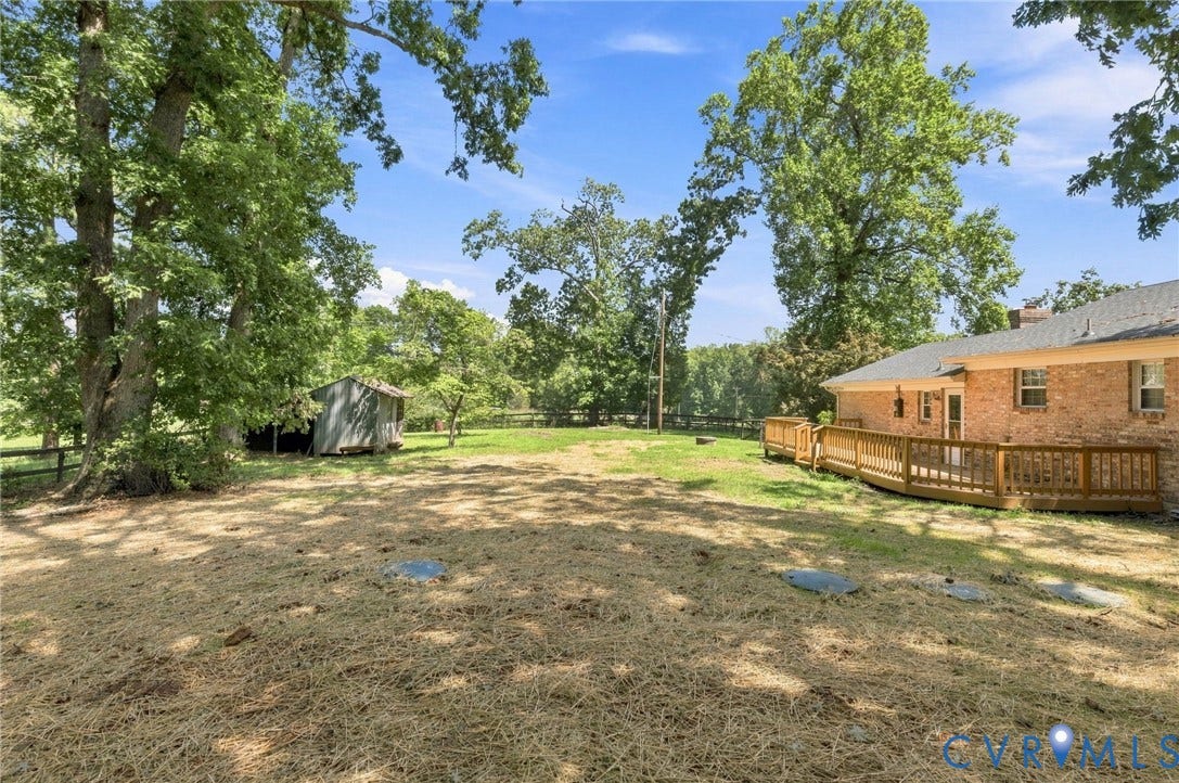 2707 Academy Road, Powhatan, VA 23139 Expansive outdoor space featuring a wood deck, mature trees, a storage shed, and a brick exterior