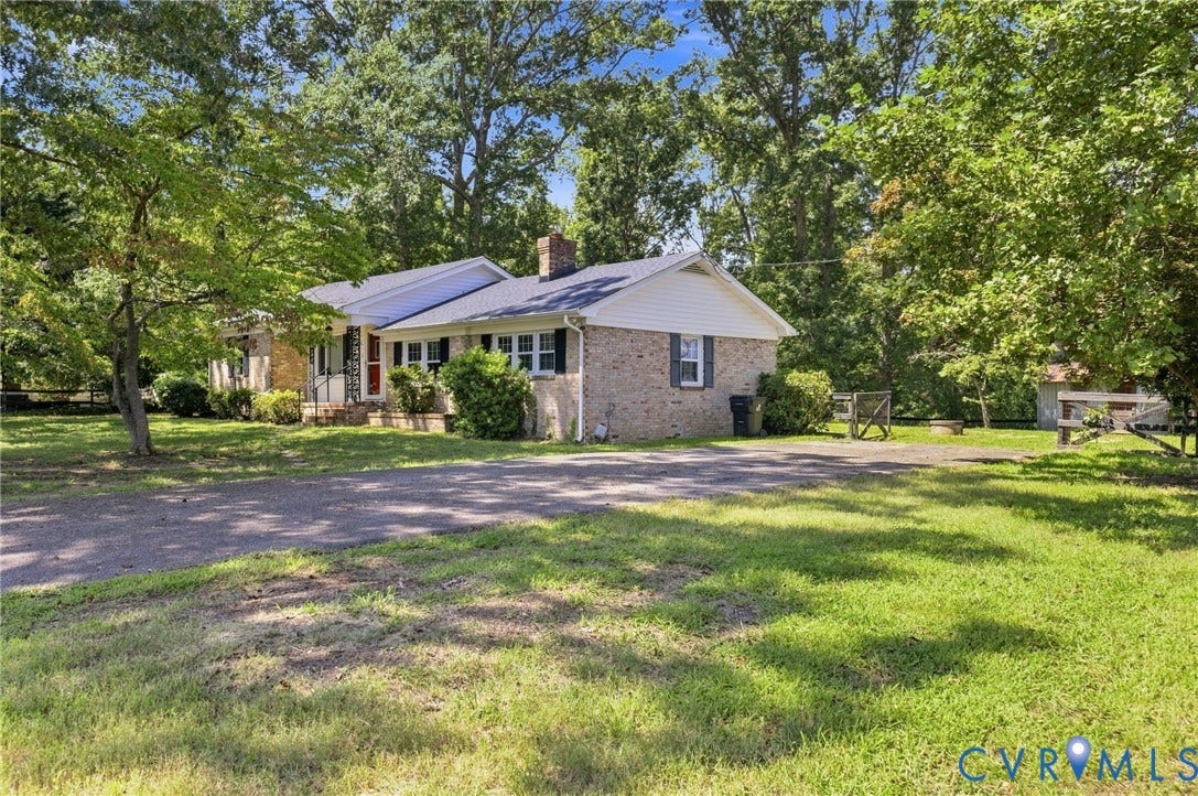 2707 Academy Road, Powhatan, VA 23139 Brick exterior with white trim, a dark-shingled roof, a front porch with a red door, and a gravel driveway