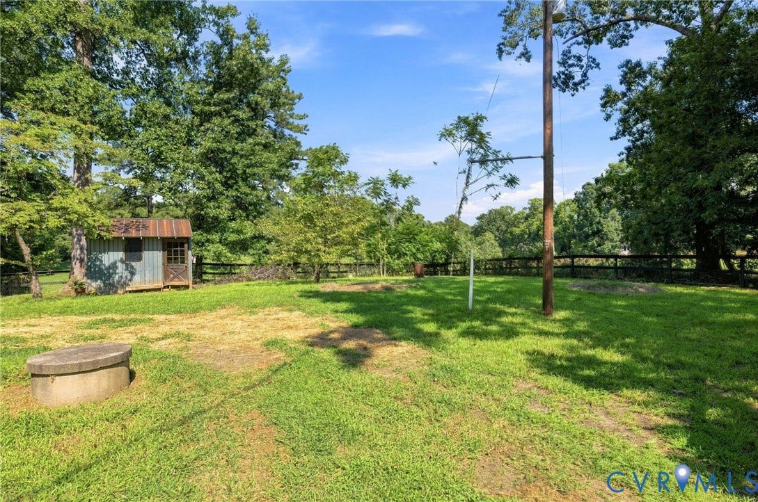 2707 Academy Road, Powhatan, VA 23139 Expansive grassy area with a rustic storage shed, perimeter fencing, and mature trees