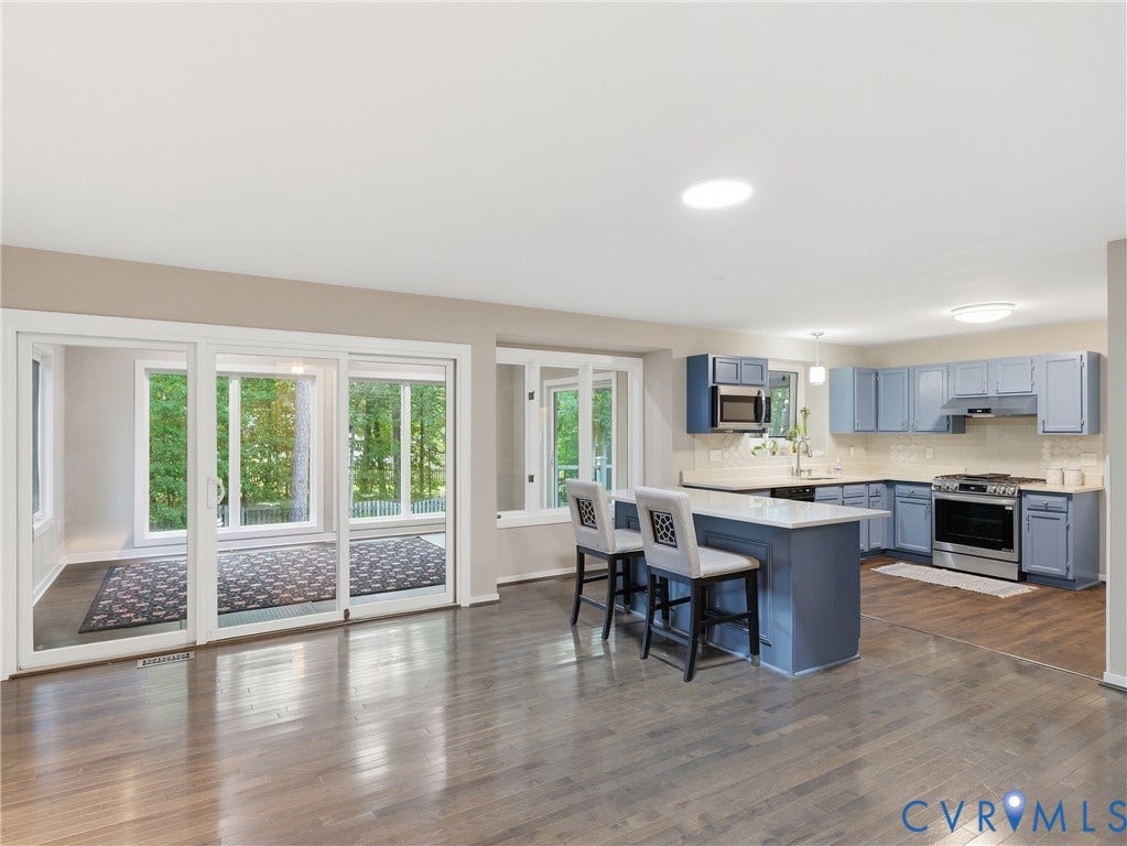Hardwood-finish flooring throughout, kitchen with blue cabinetry, stainless steel appliances, and a central island with countertop seating