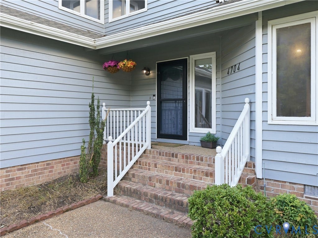 Entryway featuring a brick-clad staircase, white railings, light blue siding, and white-framed windows
