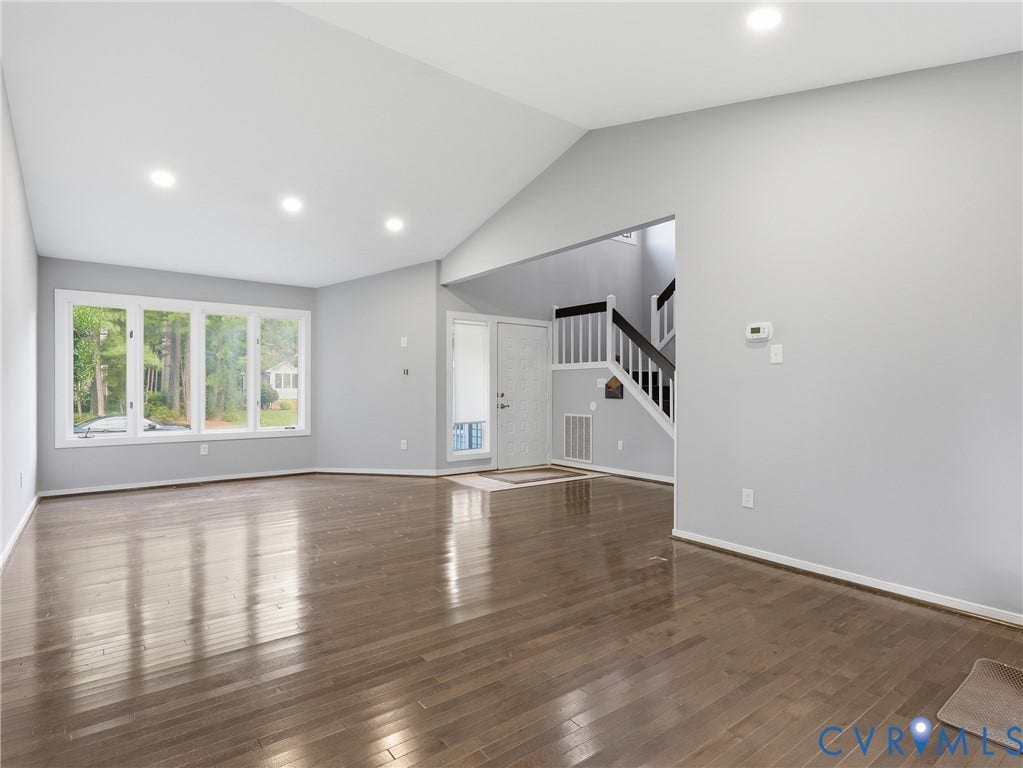 Vaulted ceiling, recessed lighting, wood-finish flooring, bay window, and a multi-level staircase
