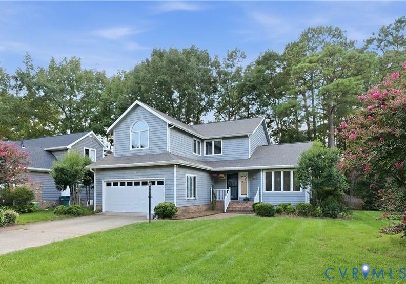 Two-story residence with light blue siding, an attached two-car garage, and a lush front lawn