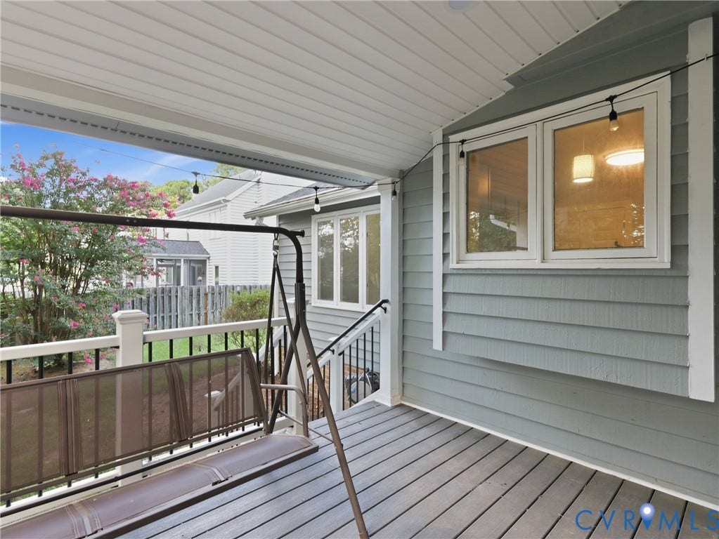 Covered porch featuring composite decking, painted railing, and horizontal siding
