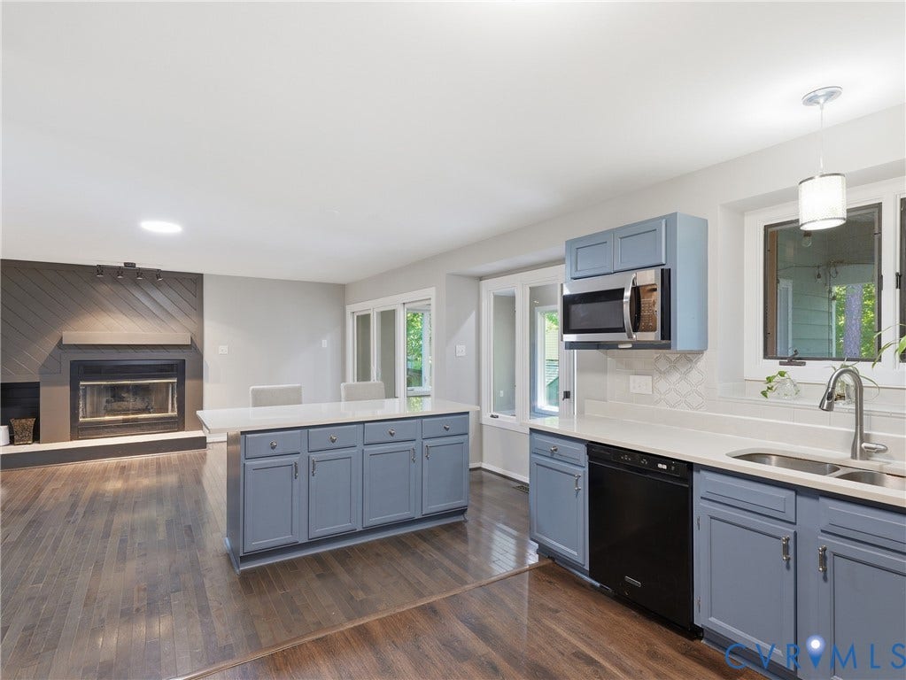 Kitchen with blue cabinetry, white countertops, stainless steel microwave, and integrated dishwasher