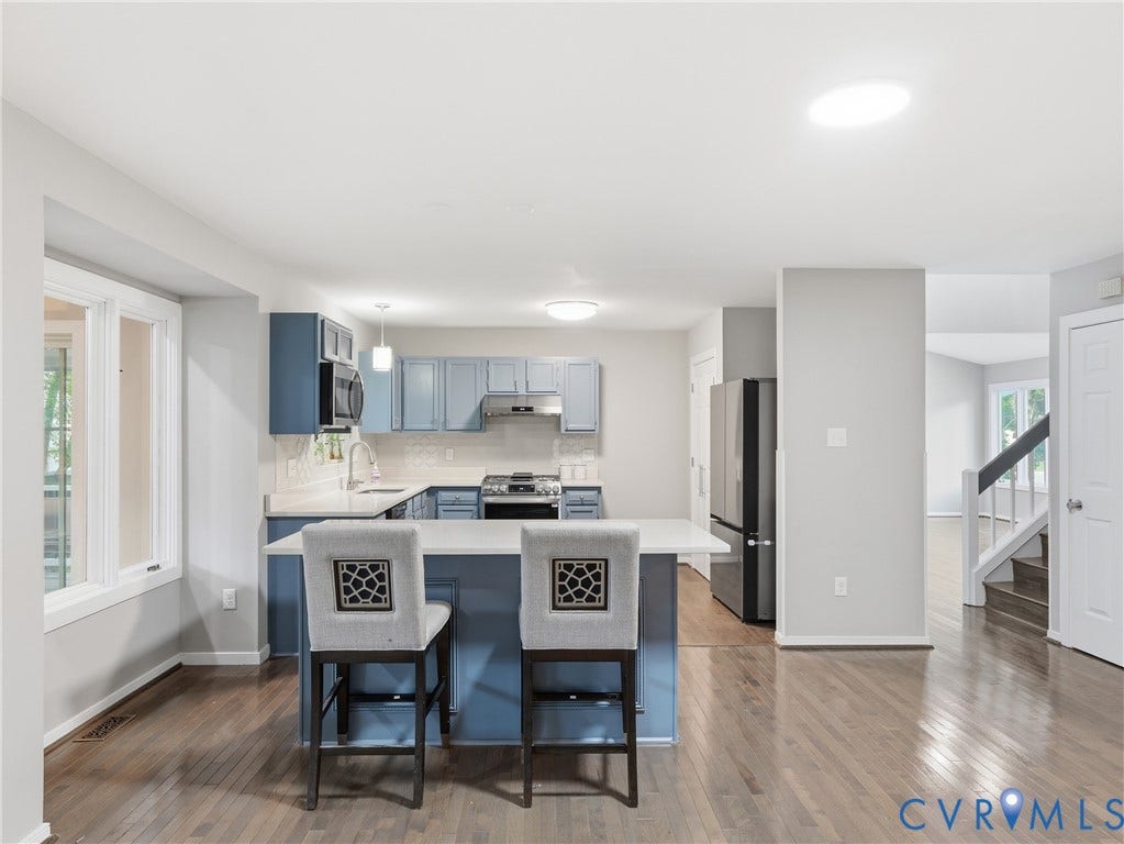 Kitchen featuring blue cabinetry, white countertops, stainless steel appliances, and a central island with seating