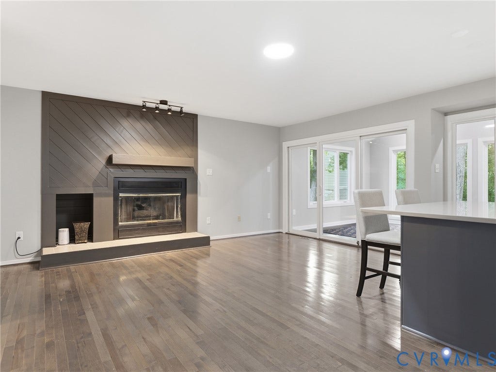Wood-finish flooring throughout, fireplace with a decorative wood mantel, recessed lighting, and sliding glass doors to exterior