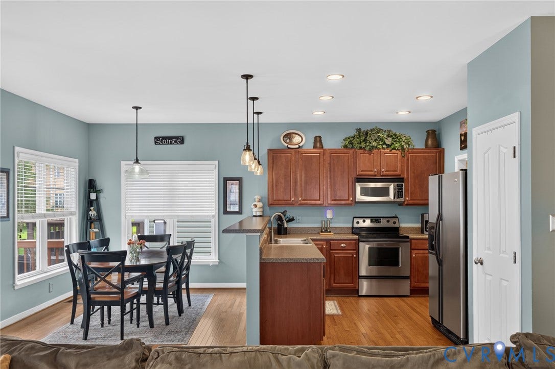 937 Gorham Court, Midlothian, VA 23114 Open-concept kitchen and dining area featuring warm wood-finish cabinetry, stainless steel appliances and hardwood flooring. This is view from family room