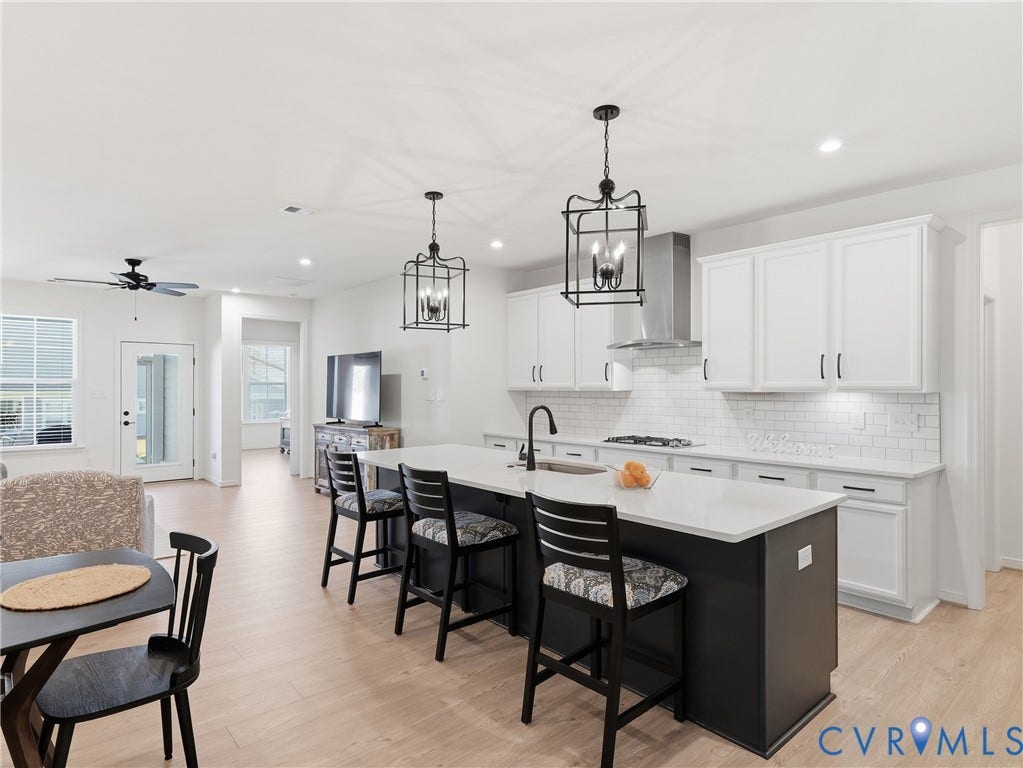 9220 Cerulean Place, Mosaic At West Creek, Goochland, VA 23238 Open-concept kitchen featuring an island with seating, white shaker cabinetry, stainless steel range hood, and subway tile backsplash
