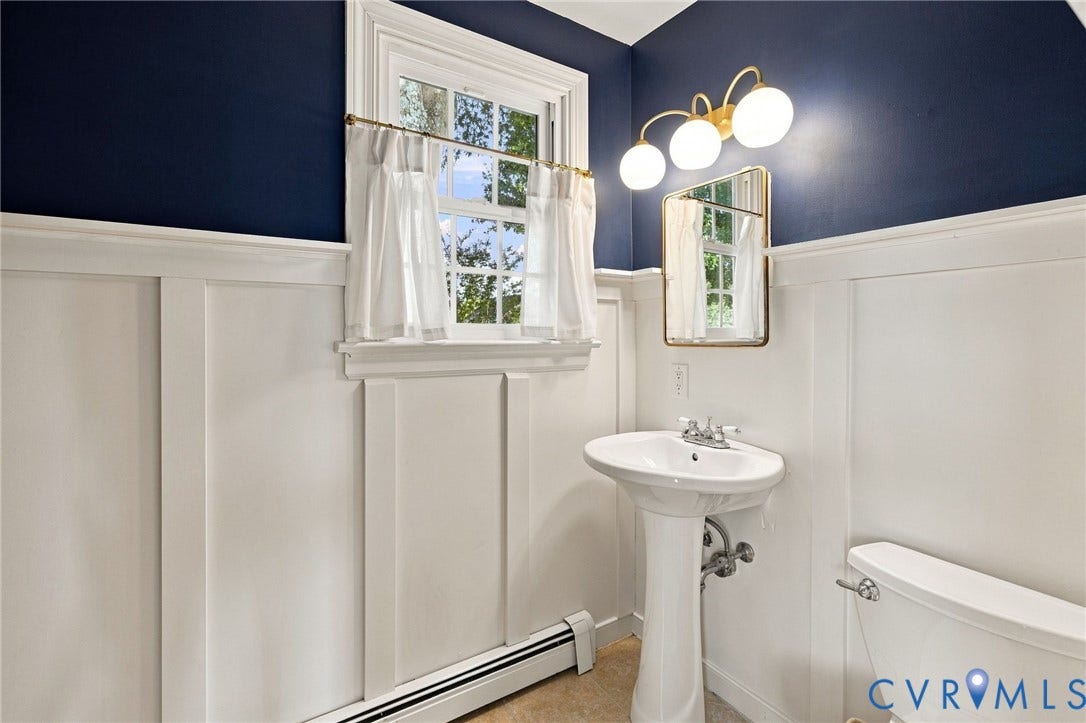 7134 Messer Road, Henrico, VA 23231 Pedestal sink with chrome faucet, board and batten wainscoting, wall-mounted mirror, and a three-light vanity fixture