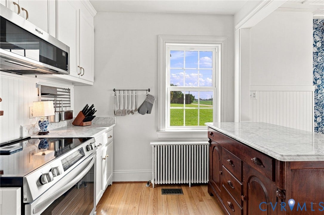 7134 Messer Road, Henrico, VA 23231 White cabinetry, stainless steel appliances, stone countertops, wood-finish flooring, and a window with a green landscape