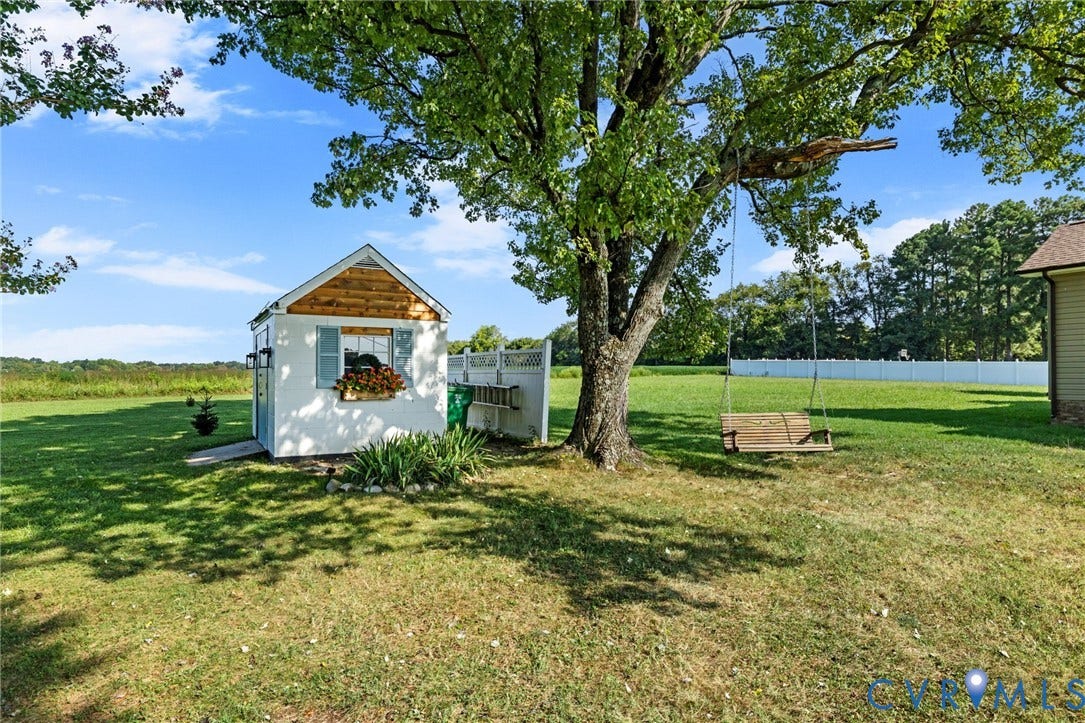 7134 Messer Road, Henrico, VA 23231 Detached storage shed with wood siding and shutters, mature tree, and expansive lawn