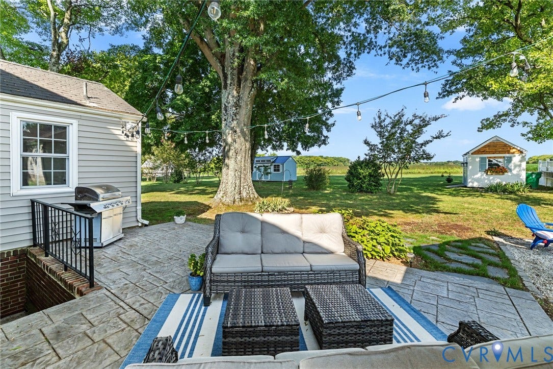 7134 Messer Road, Henrico, VA 23231 Expansive backyard featuring stone patio, string lighting, mature trees, and a detached shed