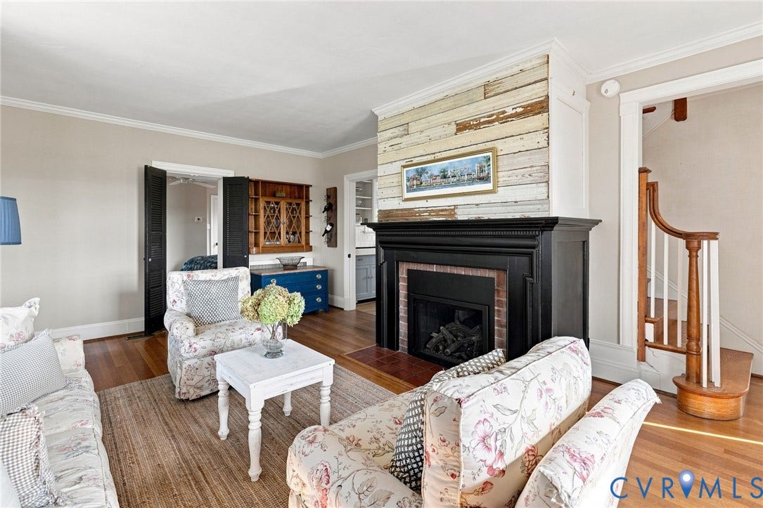 7134 Messer Road, Henrico, VA 23231 Hardwood flooring, fireplace with black mantel and brick surround, shiplap accent wall, built-in cabinetry, and a wood staircase with white balusters
