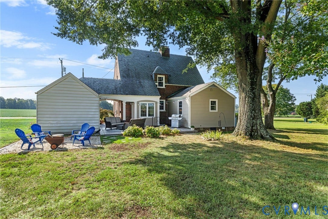 7134 Messer Road, Henrico, VA 23231 Expansive backyard featuring a manicured lawn, established shade trees, and a stone patio