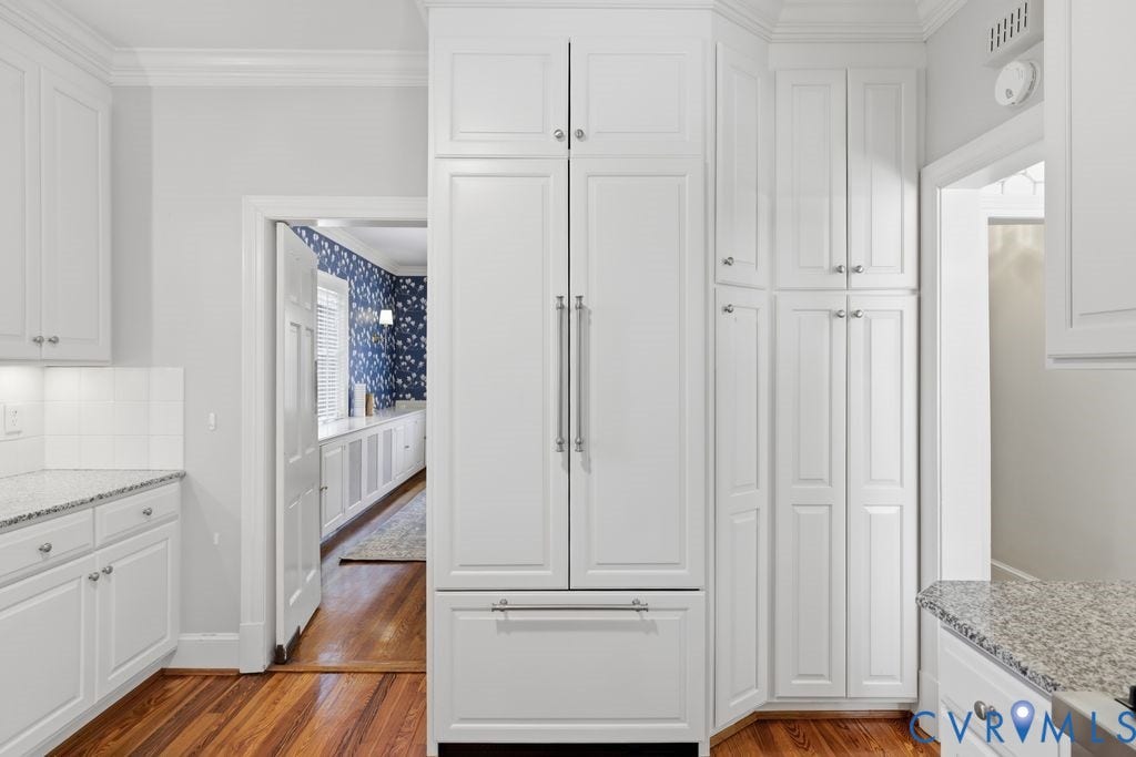 4117 W Franklin Street, Malvern Gardens, Richmond, VA 23221 Integrated refrigerator with custom paneling, white shaker cabinetry, speckled countertop, white subway tile backsplash, and wood-finish flooring