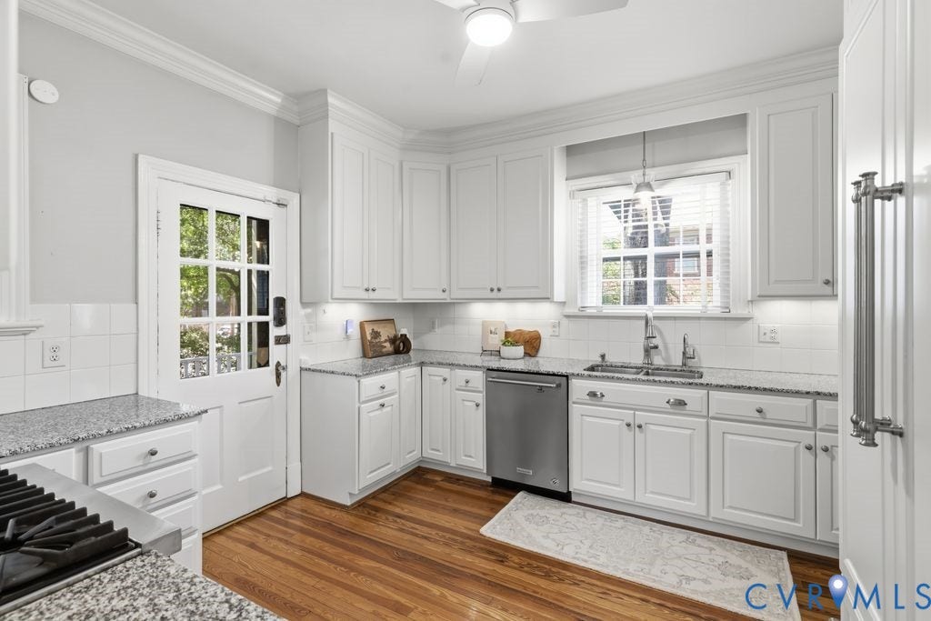 4117 W Franklin Street, Malvern Gardens, Richmond, VA 23221 White shaker-style cabinetry, stainless steel dishwasher, double basin sink with stainless steel faucet, wood-finish flooring, and white subway tile backsplash
