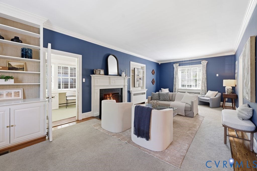 4117 W Franklin Street, Malvern Gardens, Richmond, VA 23221 Living space featuring a white mantel fireplace, built-in shelving with lower cabinetry, and crown molding
