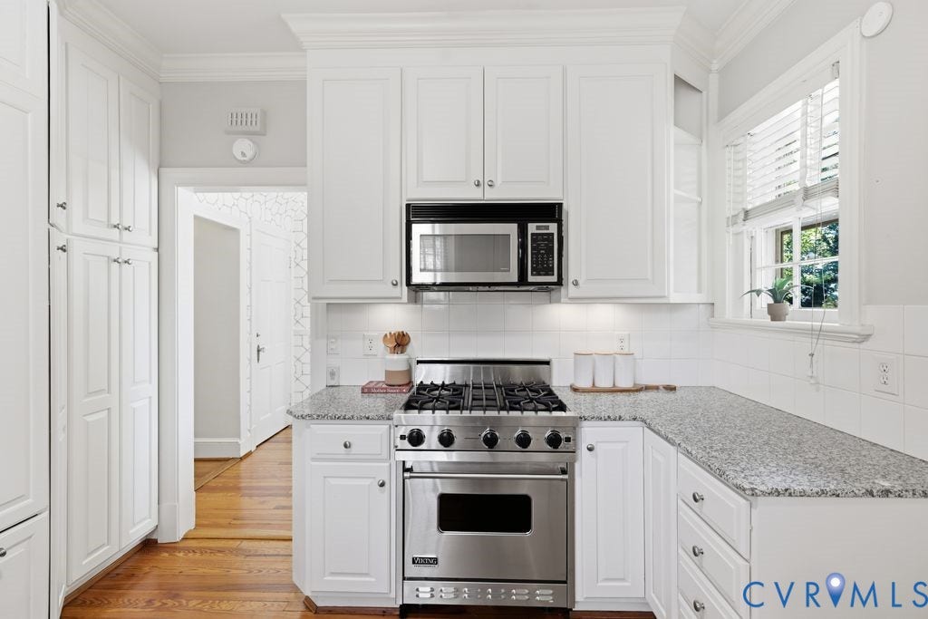 4117 W Franklin Street, Malvern Gardens, Richmond, VA 23221 White cabinetry, stainless steel range, built-in microwave, light-toned countertop, and white tile backsplash