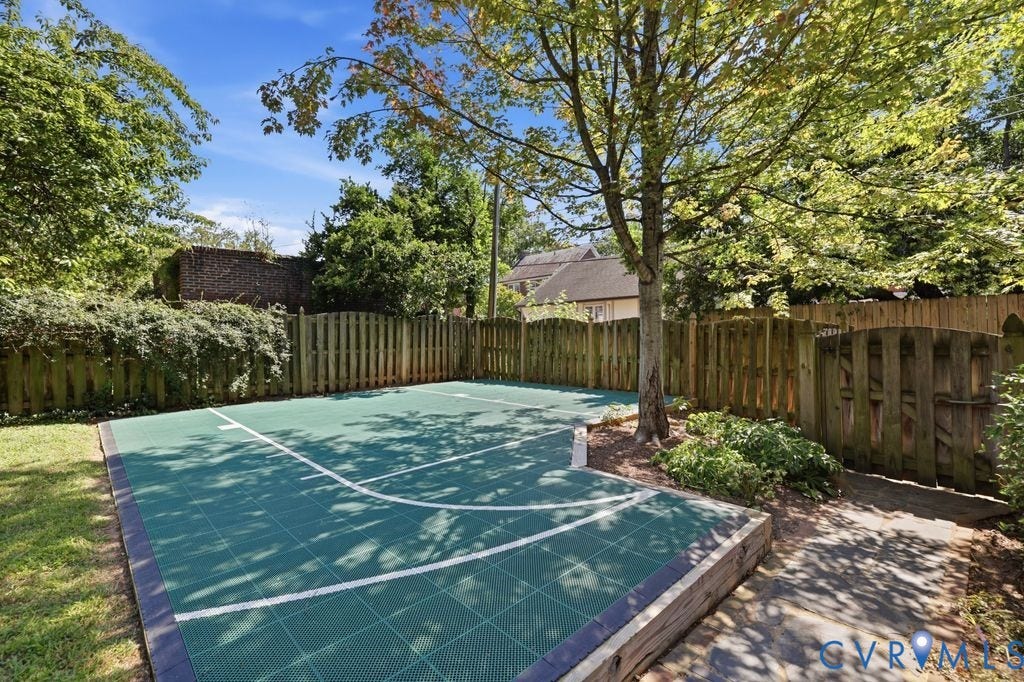 4117 W Franklin Street, Malvern Gardens, Richmond, VA 23221 Recreational court with a tiled surface, bordered by a wooden fence, mature trees, and established plantings
