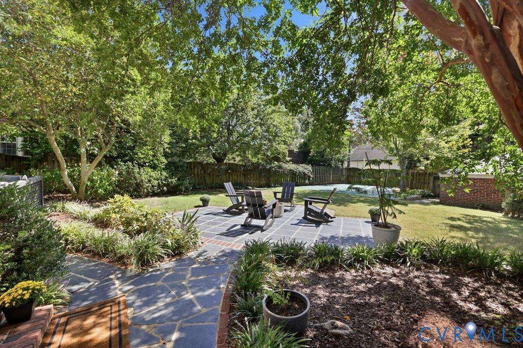 4117 W Franklin Street, Malvern Gardens, Richmond, VA 23221 Expansive backyard featuring a stone patio, manicured lawn, and mature trees, with a privacy fence