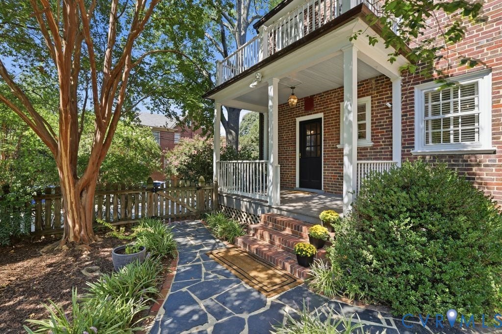 4117 W Franklin Street, Malvern Gardens, Richmond, VA 23221 Brick exterior featuring a covered porch with white columns, a second-story balcony with white railing, and a flagstone walkway