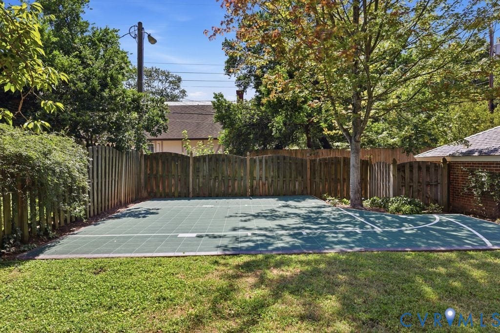 4117 W Franklin Street, Malvern Gardens, Richmond, VA 23221 Expansive outdoor court with defined markings, surrounded by a wooden privacy fence, mature trees, and a grass lawn