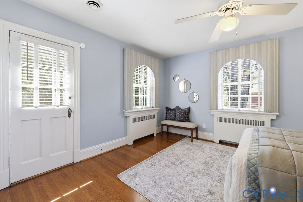 4117 W Franklin Street, Malvern Gardens, Richmond, VA 23221 Wood-finish flooring, two arched windows with blinds, a paneled door with louvered glass, and a ceiling fan with integrated lighting