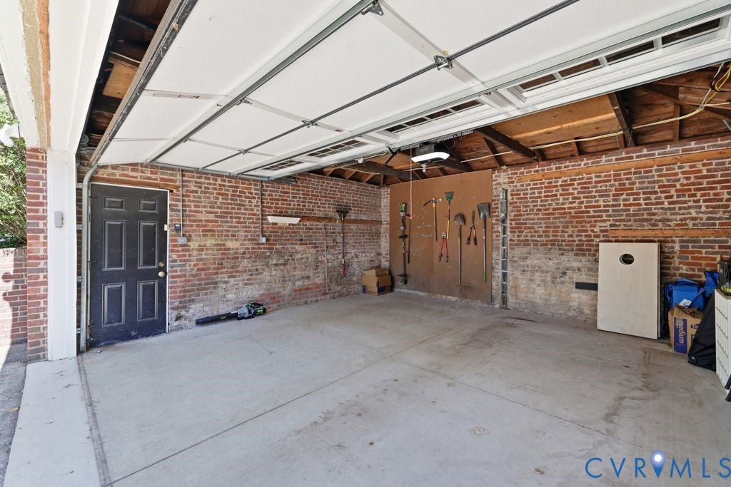 4117 W Franklin Street, Malvern Gardens, Richmond, VA 23221 Spacious garage with exposed brick walls, concrete flooring, and an overhead garage door