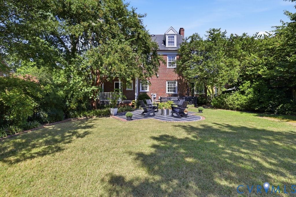4117 W Franklin Street, Malvern Gardens, Richmond, VA 23221 Expansive green lawn with a circular paver patio, mature trees, and a brick exterior with white trim