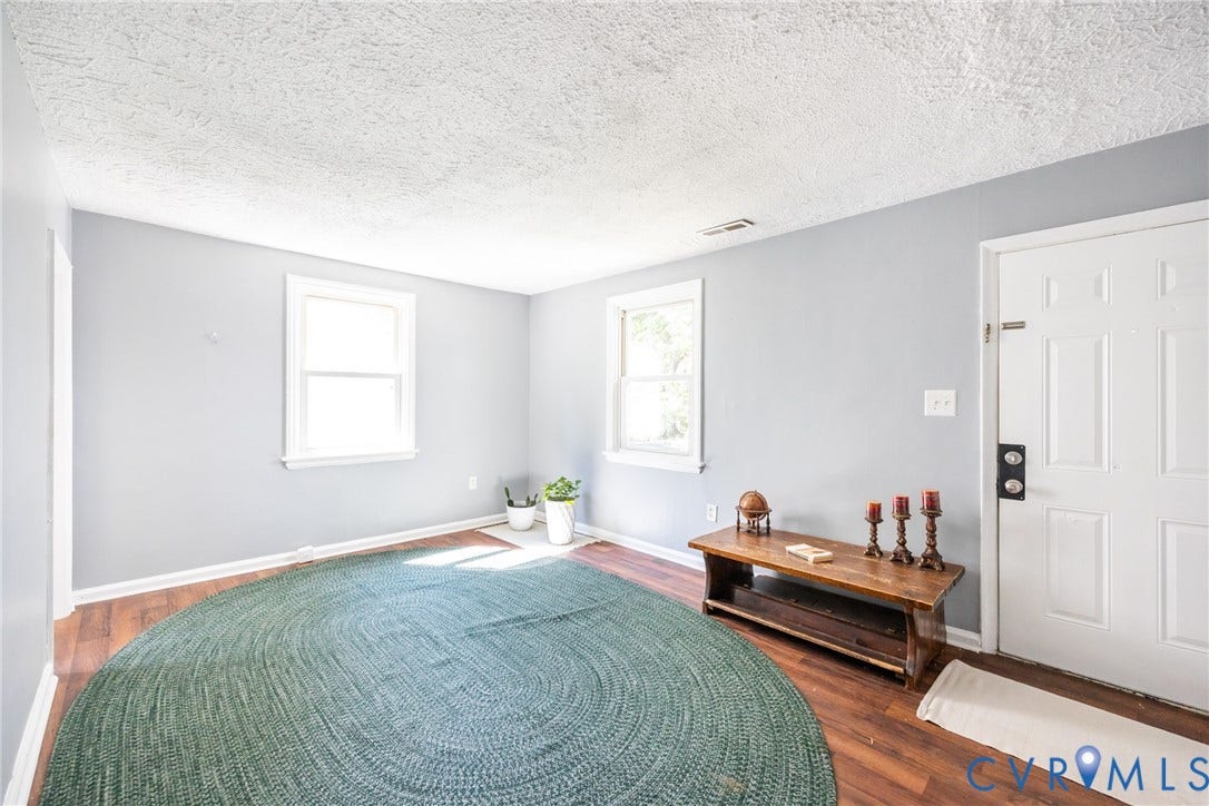 3505 Meadowbridge Road, Richmond, VA 23222 Spacious room with hardwood flooring, soft gray walls, and abundant natural light from dual windows