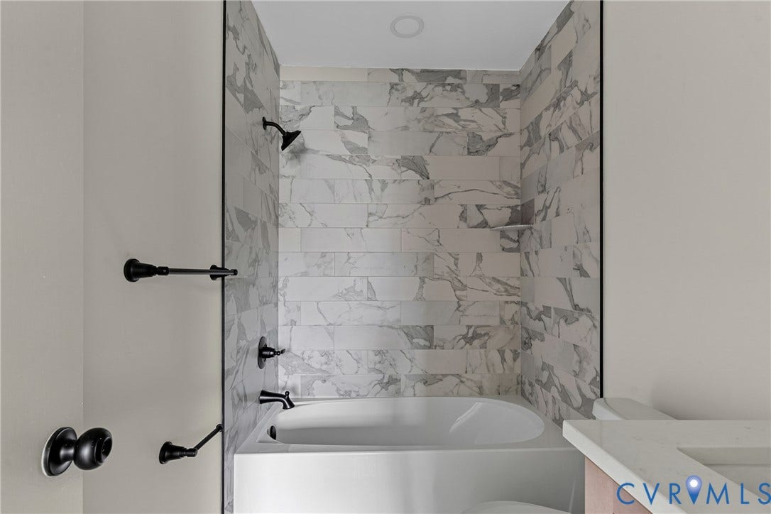 3924 Lamplighter Drive, Richmond, VA 23234 Bathtub and shower combination featuring marble-look tile surround and matte black fixtures