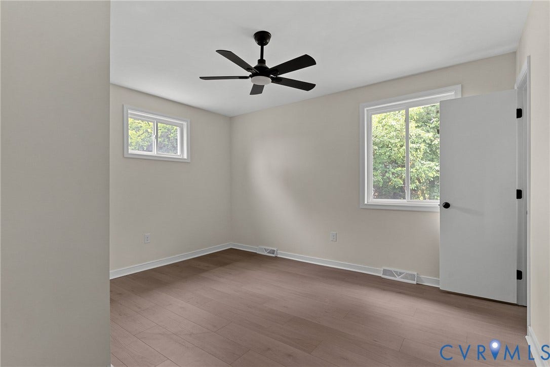 3924 Lamplighter Drive, Richmond, VA 23234 Neutral-toned room featuring wood-finish flooring, a modern black ceiling fan with lighting, white trim, and two windows providing natural illumination