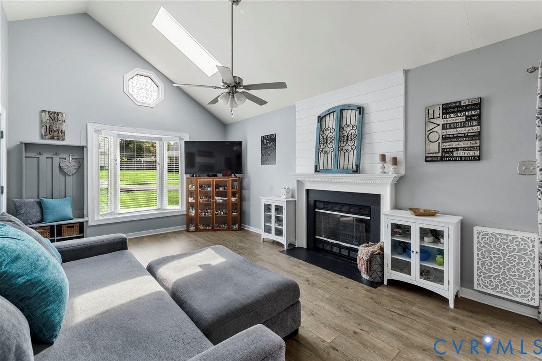 10138 Alberta Circle, Chesterfield, VA 23832 Vaulted ceiling with skylight, bay window, wood-finish flooring, fireplace with white mantel, and ceiling fan