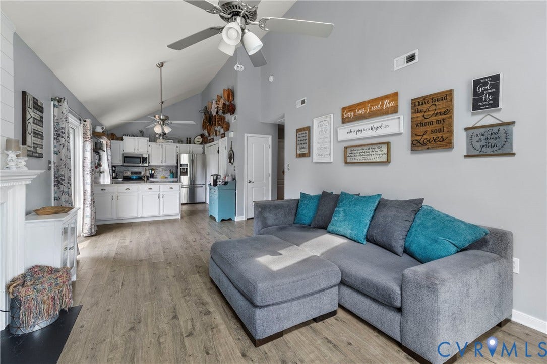 10138 Alberta Circle, Chesterfield, VA 23832 Vaulted ceiling with ceiling fans, wood-finish flooring, white kitchen cabinetry, stainless steel appliances, and a white fireplace surround