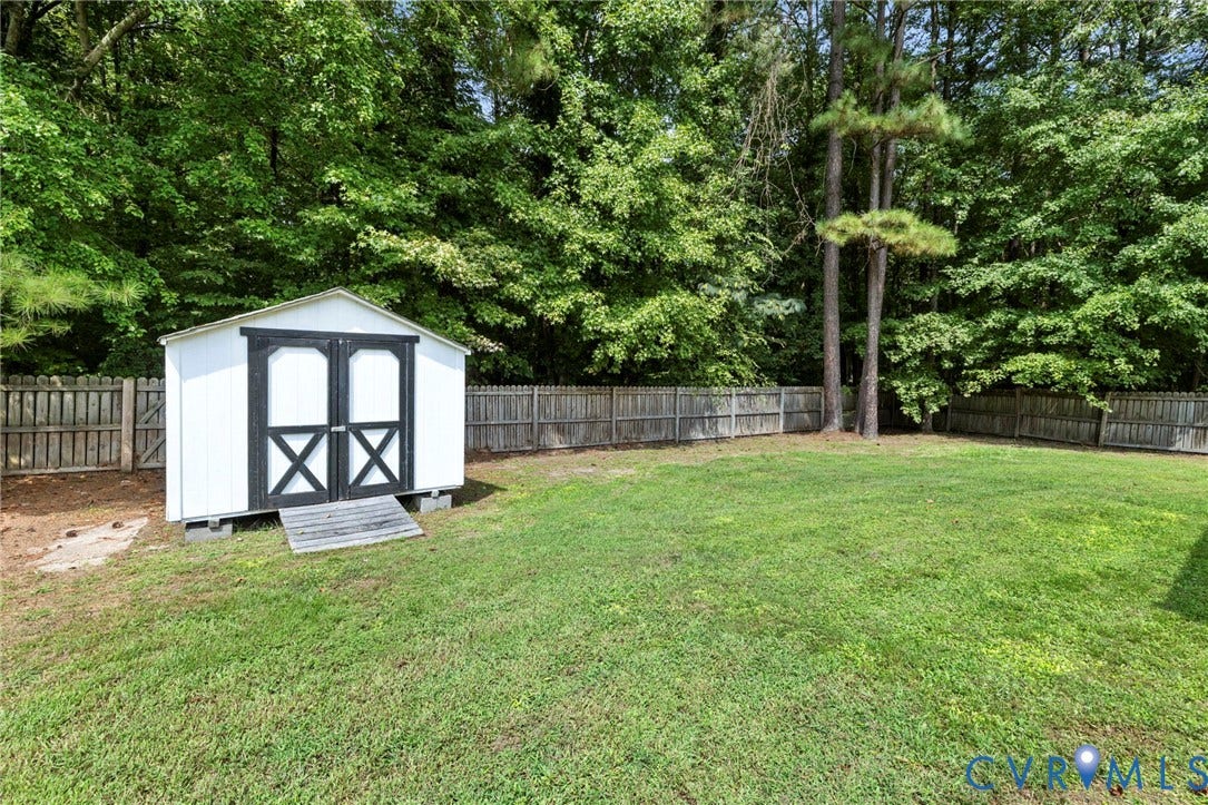 10138 Alberta Circle, Chesterfield, VA 23832 Expansive green lawn with a privacy fence, mature trees, and a freestanding storage shed featuring double black barn doors and a ramp entrance